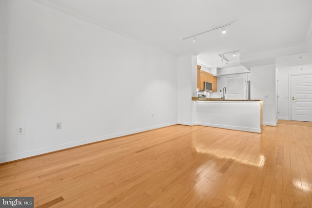 unfurnished living room with sink and light hardwood / wood-style floors