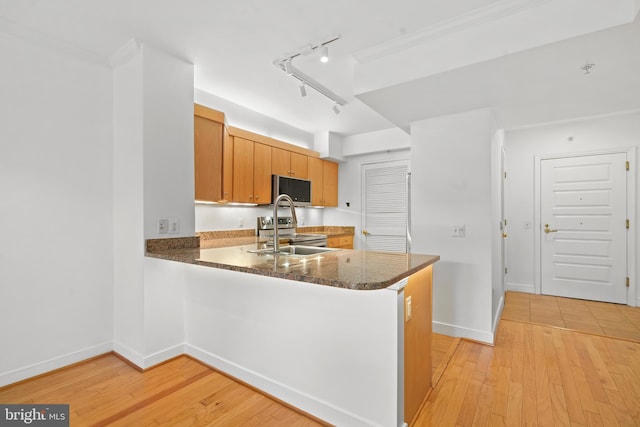 kitchen featuring sink, light hardwood / wood-style floors, stainless steel range with electric cooktop, kitchen peninsula, and dark stone counters