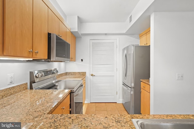 kitchen with stainless steel appliances, light stone countertops, and light tile patterned floors