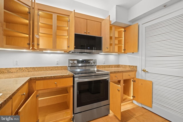 kitchen featuring stainless steel appliances, light stone countertops, and light tile patterned floors