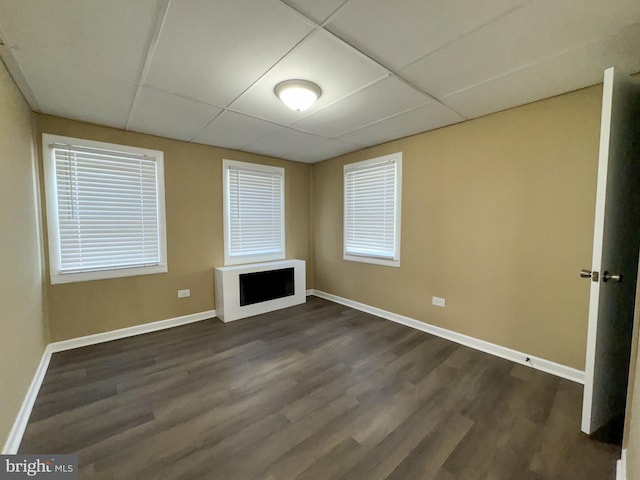 unfurnished living room with a paneled ceiling and dark hardwood / wood-style floors