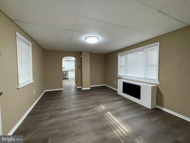 unfurnished living room featuring dark hardwood / wood-style floors, sink, and a drop ceiling