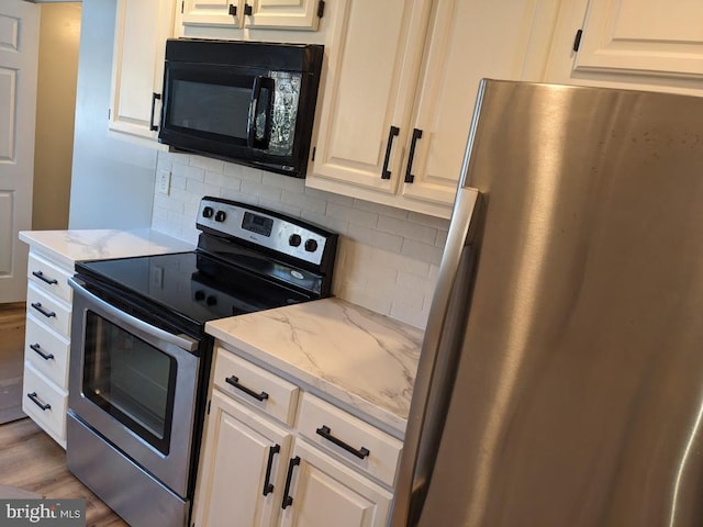 kitchen featuring white cabinetry, light stone counters, stainless steel appliances, light hardwood / wood-style floors, and decorative backsplash