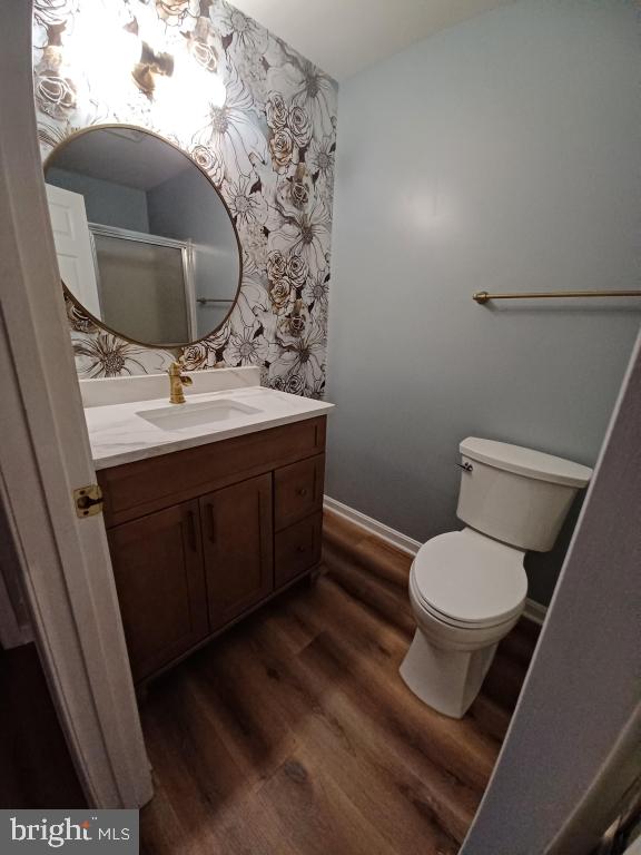 bathroom with wood-type flooring, toilet, and vanity