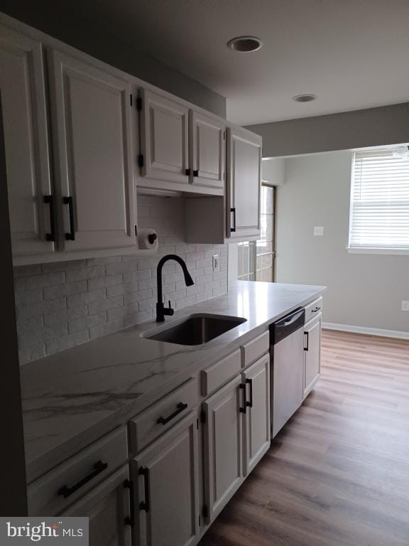 kitchen featuring sink, white cabinetry, backsplash, stainless steel dishwasher, and light wood-type flooring