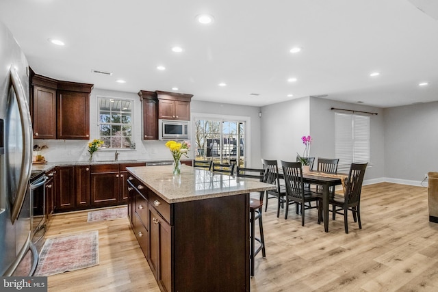 kitchen featuring plenty of natural light, stainless steel appliances, a kitchen breakfast bar, a kitchen island, and light wood-type flooring