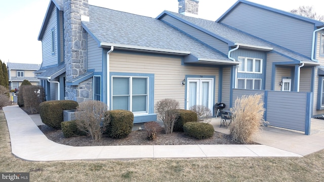 view of front of property with a patio area, a chimney, and roof with shingles