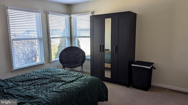 bedroom with visible vents, light colored carpet, and baseboards