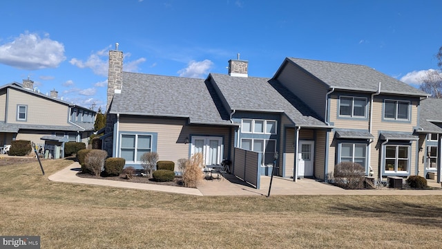 rear view of house with a patio area, a lawn, and a chimney