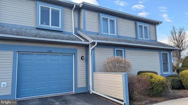 exterior space featuring an attached garage, driveway, and a shingled roof