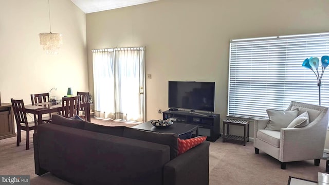 living room featuring an inviting chandelier, carpet floors, and vaulted ceiling