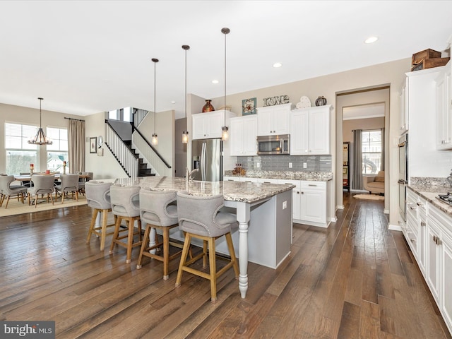 kitchen featuring appliances with stainless steel finishes, dark wood-style flooring, plenty of natural light, and tasteful backsplash