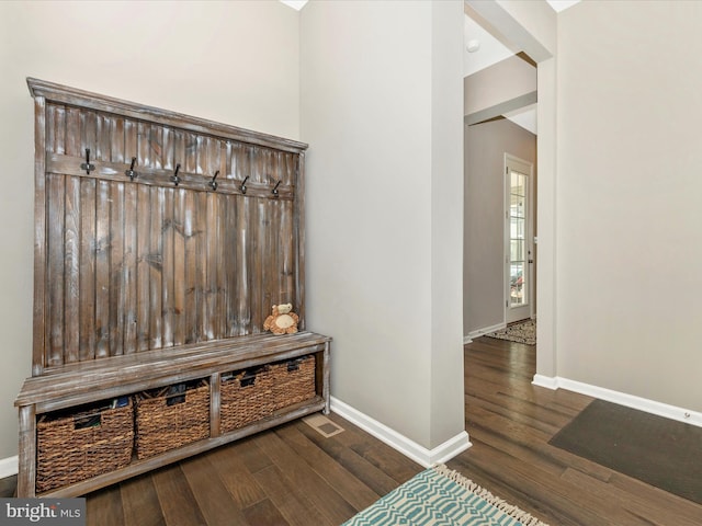 mudroom with dark wood finished floors and baseboards