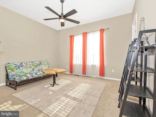 living area featuring carpet floors, baseboards, and a ceiling fan