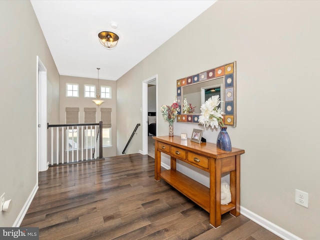 corridor featuring baseboards, wood finished floors, and an upstairs landing