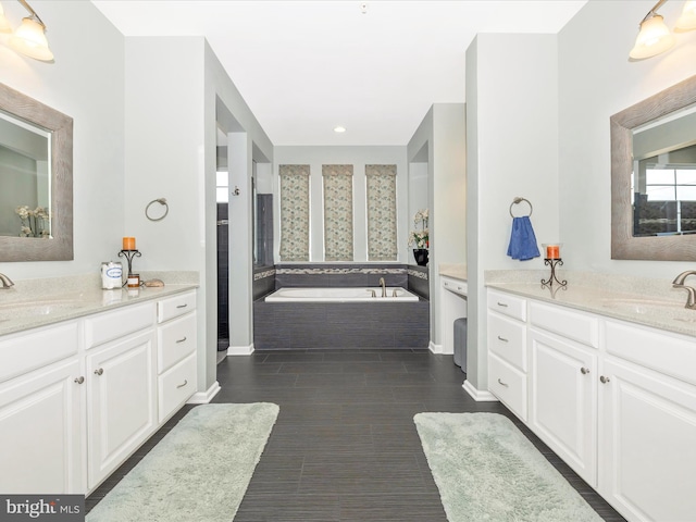 full bath featuring a bath, two vanities, and a sink