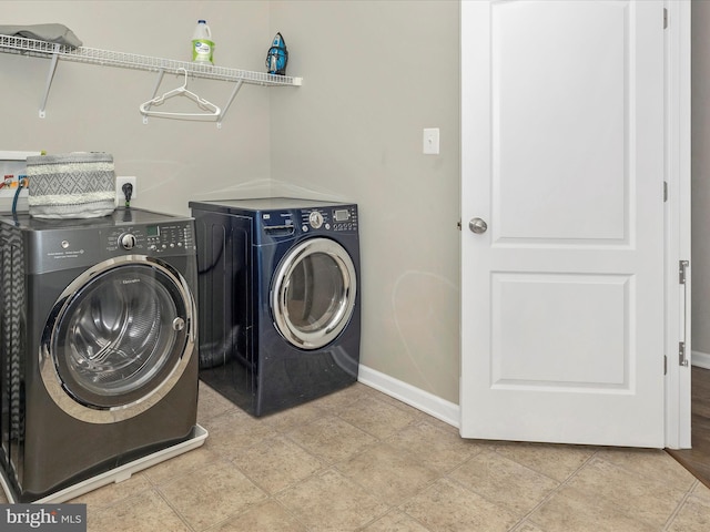 laundry area featuring baseboards, laundry area, light tile patterned flooring, and washer and dryer