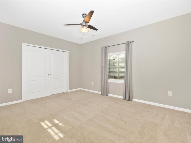 unfurnished bedroom with carpet floors, a closet, baseboards, and a ceiling fan