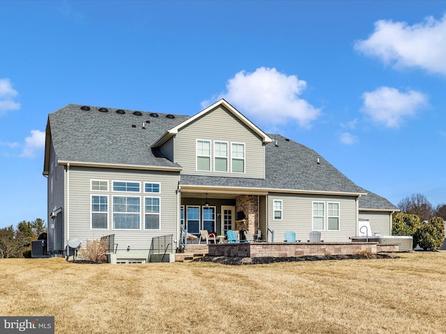 back of property with a patio, a lawn, cooling unit, and roof with shingles