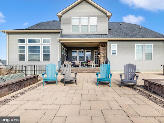 back of property with a shingled roof and a patio area