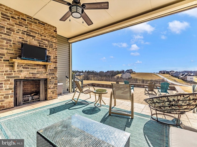 view of patio with an outdoor brick fireplace and ceiling fan