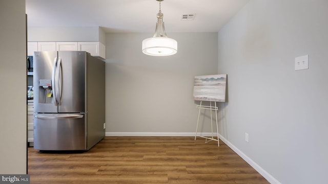 kitchen with wood finished floors, visible vents, baseboards, stainless steel fridge with ice dispenser, and white cabinetry