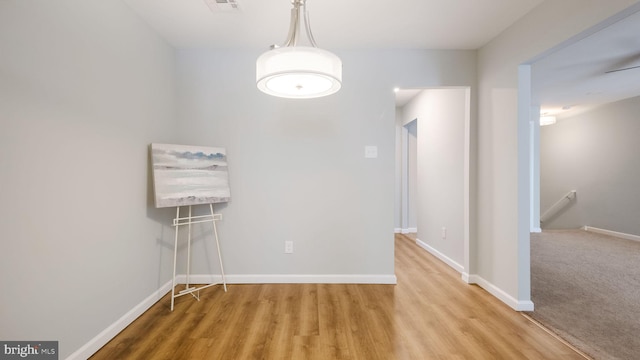 unfurnished dining area featuring visible vents, baseboards, and wood finished floors