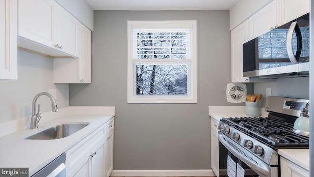 kitchen with white cabinets, appliances with stainless steel finishes, light countertops, and a sink