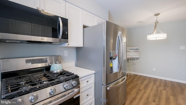 kitchen featuring wood finished floors, white cabinetry, stainless steel appliances, light countertops, and baseboards