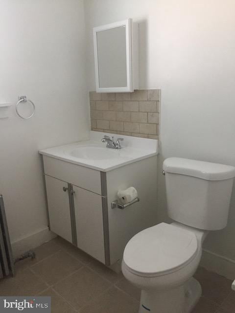 bathroom with tile patterned flooring, vanity, tasteful backsplash, and toilet