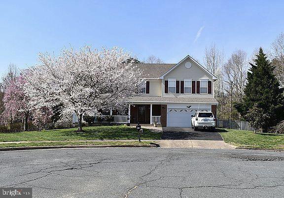 front facade featuring a garage, a porch, and a front lawn