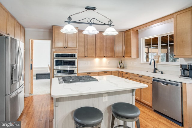 kitchen with appliances with stainless steel finishes, a breakfast bar, a kitchen island, and light wood finished floors