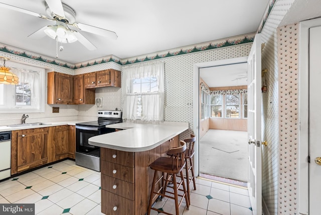 kitchen featuring sink, a healthy amount of sunlight, a kitchen bar, stainless steel electric stove, and kitchen peninsula