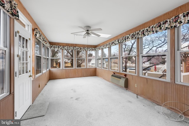 unfurnished sunroom with a wall unit AC and ceiling fan