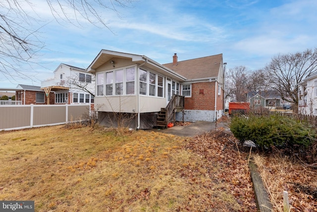 rear view of house with a sunroom and a yard