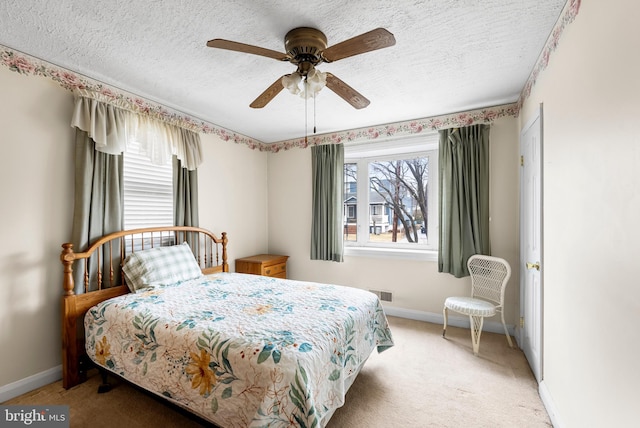 bedroom featuring ceiling fan, light colored carpet, and a textured ceiling