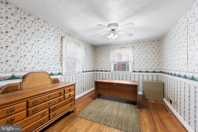 bedroom featuring hardwood / wood-style flooring, ceiling fan, and a textured ceiling