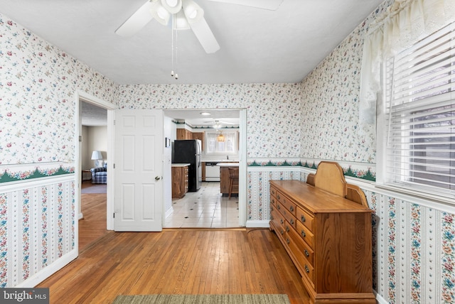 interior space with light hardwood / wood-style flooring, dishwasher, stainless steel refrigerator, and ceiling fan