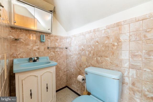 bathroom featuring vanity, vaulted ceiling, tile walls, and toilet