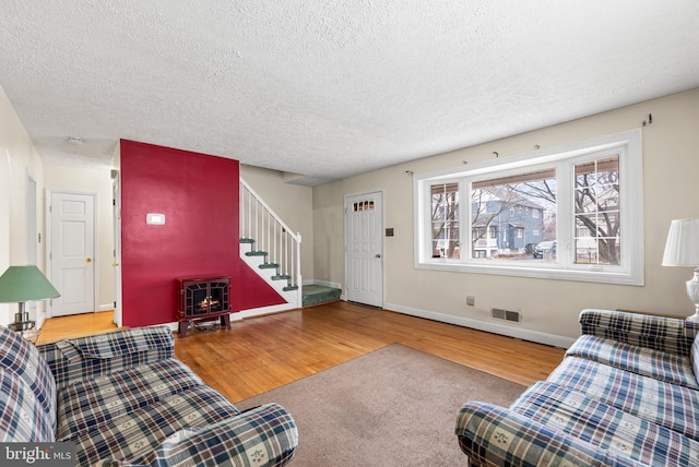 living room featuring hardwood / wood-style floors, a textured ceiling, and a wood stove