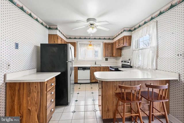 kitchen featuring a breakfast bar, sink, appliances with stainless steel finishes, kitchen peninsula, and ceiling fan