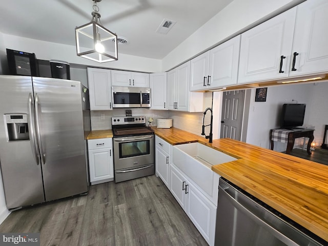 kitchen with wood counters, white cabinets, visible vents, and stainless steel appliances