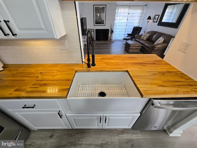 kitchen featuring white cabinetry, open floor plan, stainless steel dishwasher, and butcher block counters