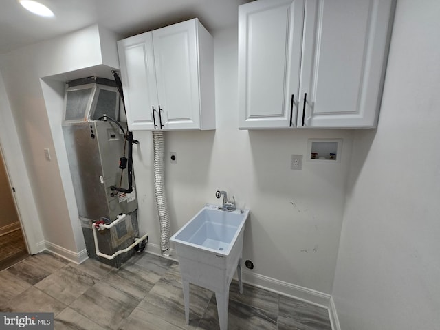 washroom with baseboards, hookup for a washing machine, cabinet space, electric dryer hookup, and a sink