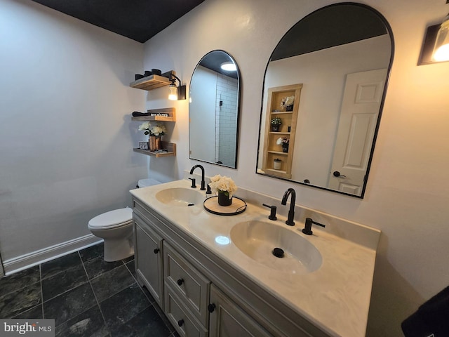 full bathroom featuring double vanity, toilet, baseboards, and a sink