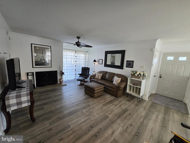 living room featuring ornamental molding, baseboards, a ceiling fan, and wood finished floors