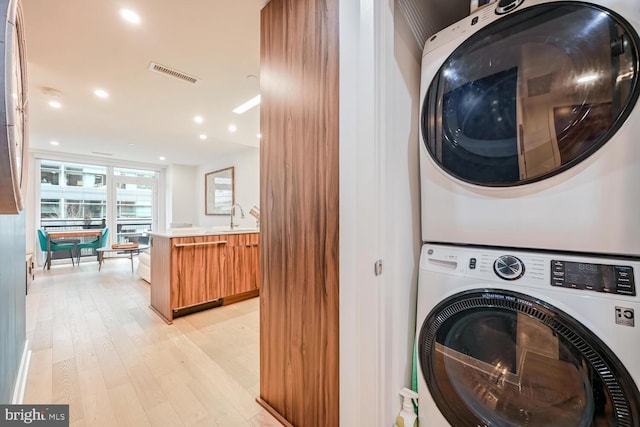 washroom with stacked washer / dryer, sink, and light wood-type flooring