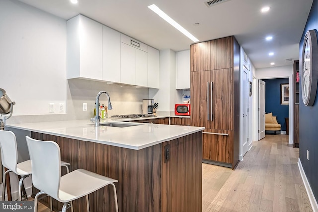 kitchen featuring white cabinetry, sink, a breakfast bar area, and kitchen peninsula