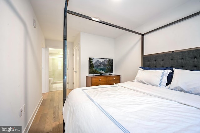 bedroom with connected bathroom and light wood-type flooring