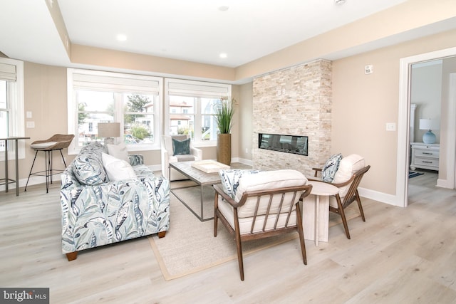 living room featuring a stone fireplace and light hardwood / wood-style floors